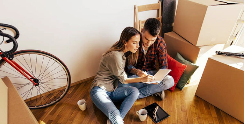 young couple sitting on the floor and preparing the moving checklist