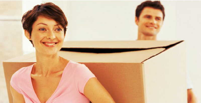 happy couple carrying a big box together