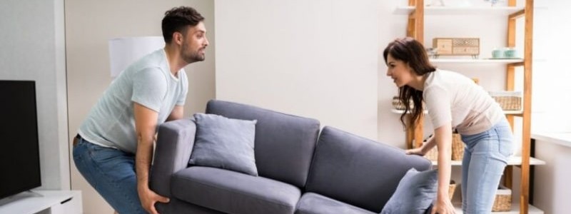 young couple trying to move a couch