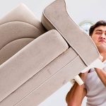 young man trying to lift a heavy couch