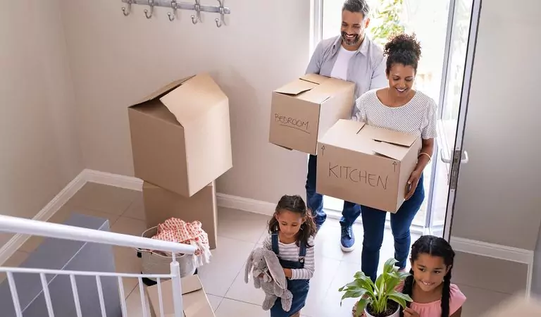 family with cardboard boxes heading inside of their new house