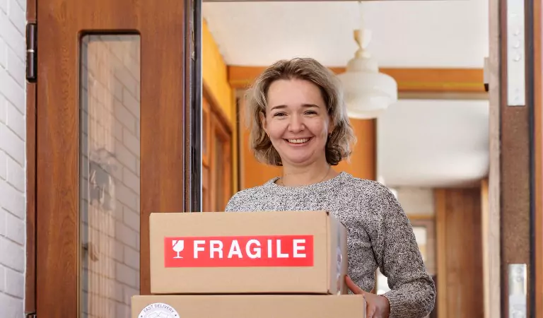 woman holding a box of fragile items and smiling