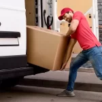 young professional trying to load a heavy cardboard into a van