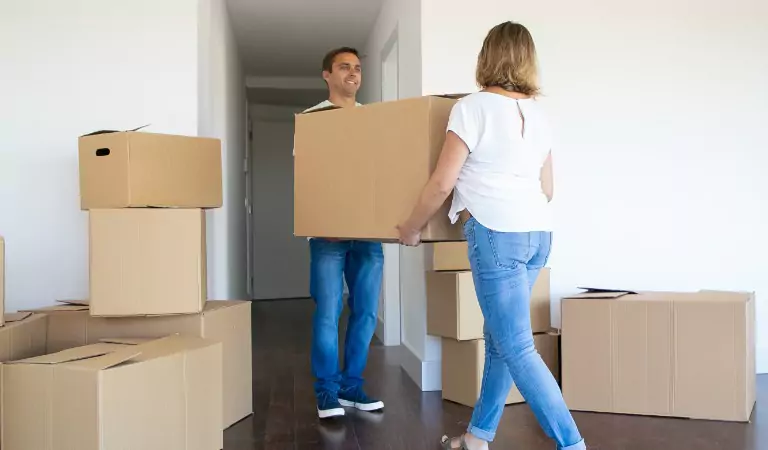 couple trying to lift heavy cardboard box during the moving